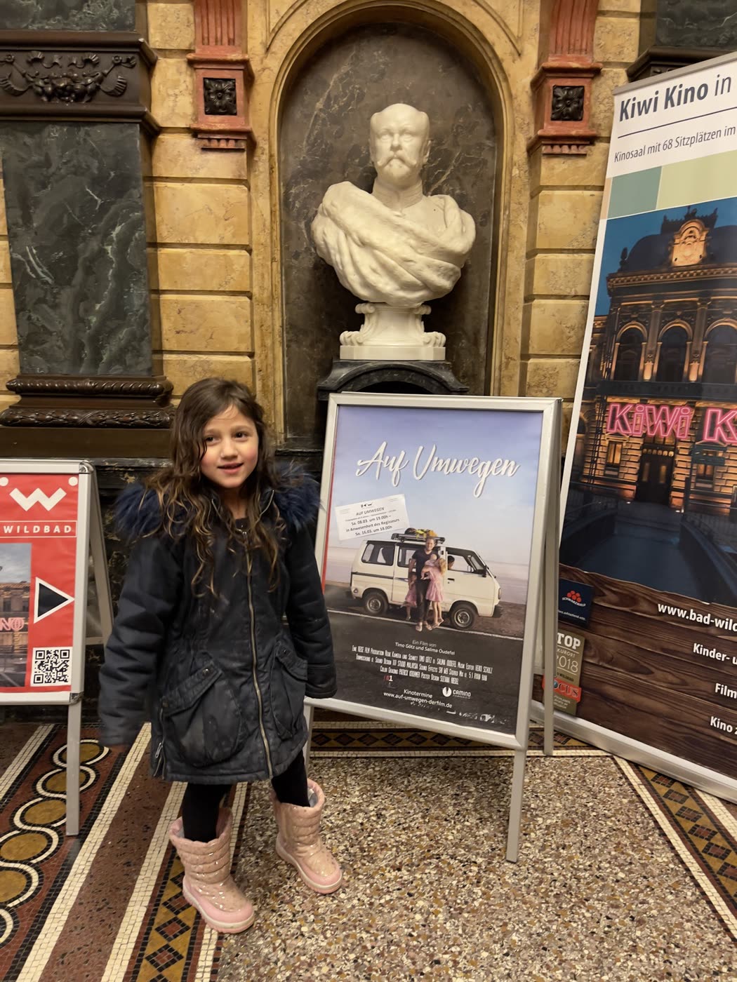 Tochter neben dem Filmplakat am Kino